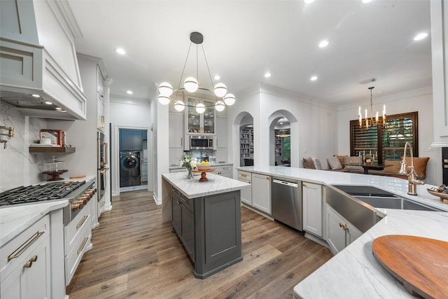 1924 Boulder Ridge Dr, Conroe, TX 77304 - kitchen with appliances with stainless steel finishes, a chandelier, a sink, arched walkways, and crown molding