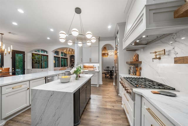 1924 Boulder Ridge Dr, Conroe, TX 77304 - kitchen with a chandelier, custom range hood, a kitchen island with sink, arched walkways, and ornamental molding