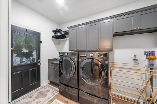 laundry area with cabinet space, light wood finished floors, and washing machine and clothes dryer