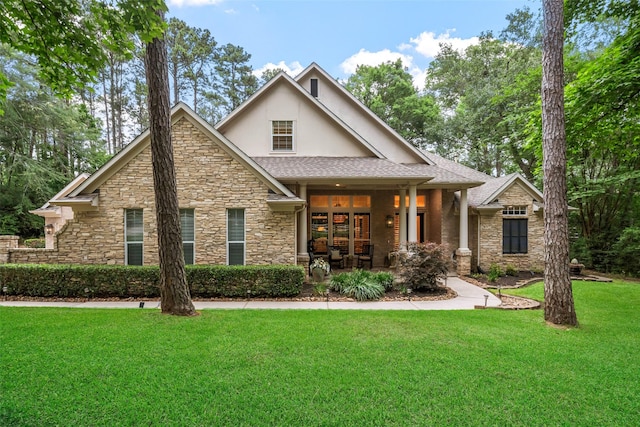 1924 Boulder Ridge Dr, Conroe, TX 77304 - craftsman-style house with stucco siding, stone siding, a front yard, a shingled roof, and a porch