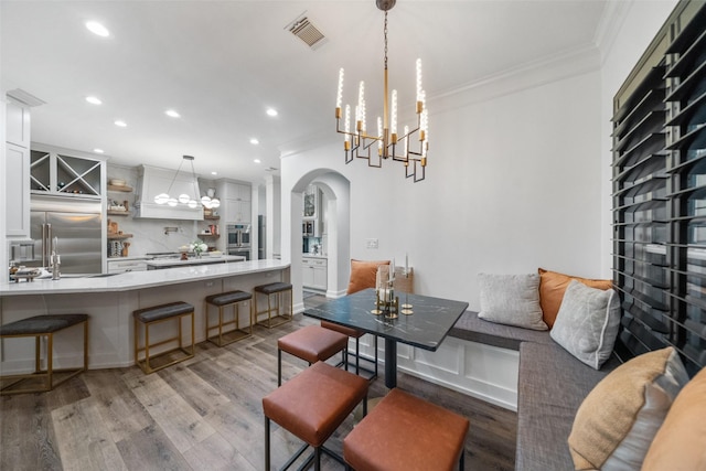 1924 Boulder Ridge Dr, Conroe, TX 77304 - dining space with ornamental molding, arched walkways, light wood finished floors, recessed lighting, and a chandelier