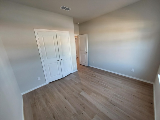 unfurnished bedroom featuring wood finished floors, baseboards, and a closet