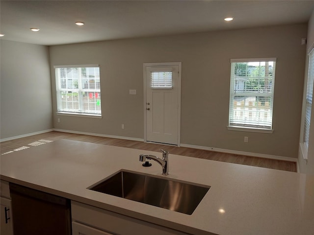 kitchen with a sink, dishwashing machine, light countertops, light wood-style flooring, and recessed lighting