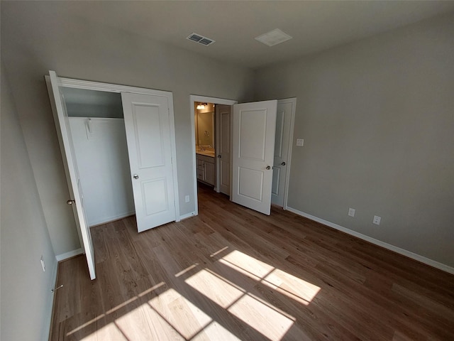 unfurnished bedroom featuring wood finished floors, baseboards, and a closet