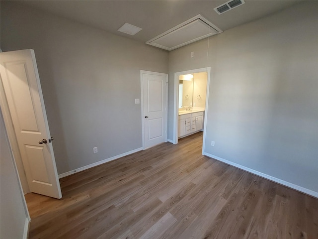unfurnished bedroom with attic access, wood finished floors, and baseboards