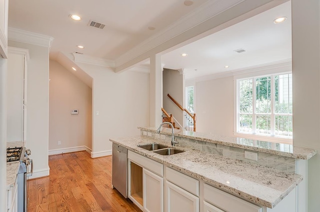 kitchen with a sink, appliances with stainless steel finishes, ornamental molding, light wood-style floors, and white cabinets