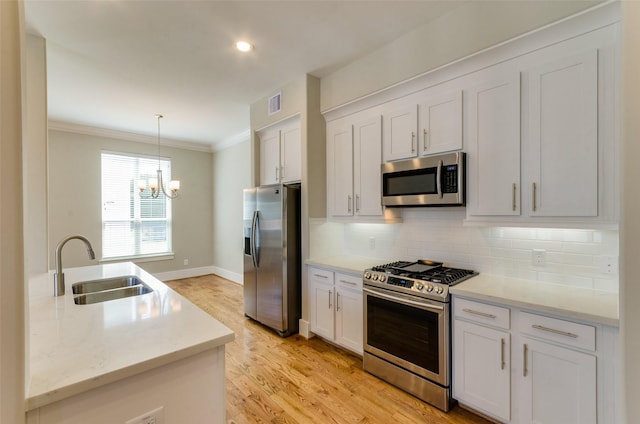 kitchen featuring stainless steel appliances, a sink, ornamental molding, a chandelier, and tasteful backsplash
