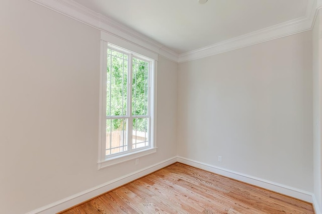 unfurnished room with plenty of natural light, crown molding, baseboards, and light wood-type flooring
