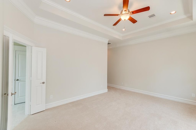 empty room featuring a raised ceiling, a ceiling fan, light carpet, crown molding, and recessed lighting