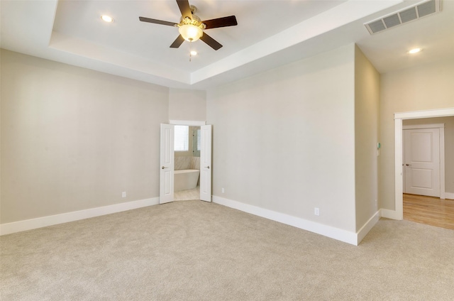 unfurnished room with light carpet, a ceiling fan, baseboards, recessed lighting, and a raised ceiling