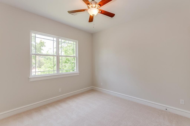 spare room featuring light carpet, baseboards, and ceiling fan