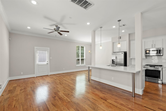 kitchen featuring appliances with stainless steel finishes, crown molding, a breakfast bar area, ceiling fan, and recessed lighting