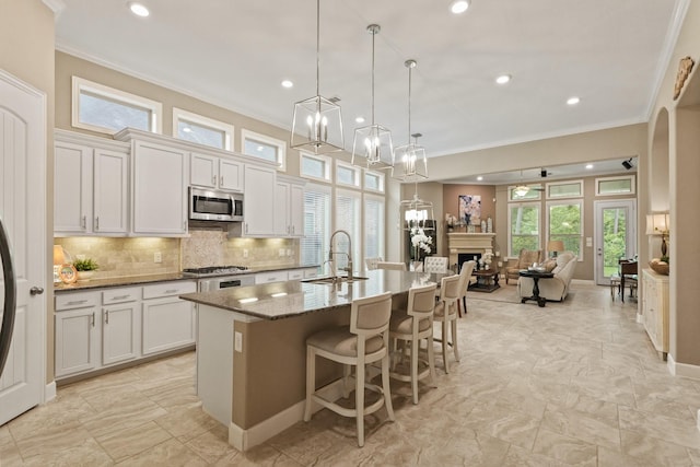 514 Pearl View Ln, Pinehurst, TX 77362 - kitchen with appliances with stainless steel finishes, a sink, ornamental molding, an island with sink, and open floor plan