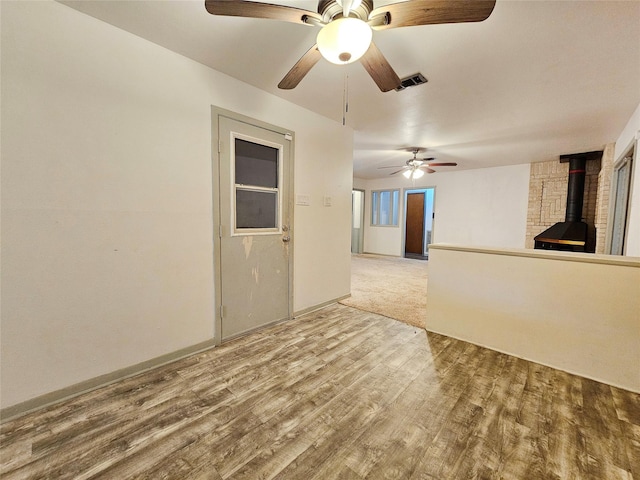 807 Golf Ct, Stafford, TX 77477 - empty room with a wood stove, a ceiling fan, wood finished floors, and baseboards
