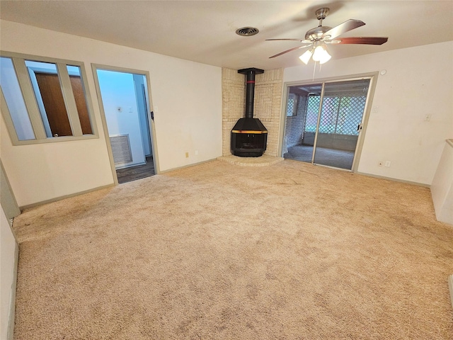 807 Golf Ct, Stafford, TX 77477 - unfurnished living room featuring a wood stove, a ceiling fan, carpet flooring, and baseboards