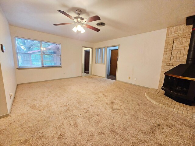 807 Golf Ct, Stafford, TX 77477 - unfurnished living room featuring a wood stove, carpet, and ceiling fan