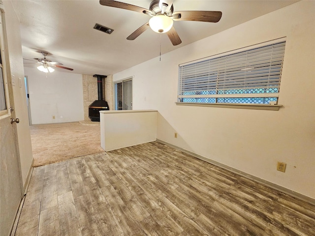 807 Golf Ct, Stafford, TX 77477 - unfurnished living room featuring a wood stove, ceiling fan, wood finished floors, and baseboards