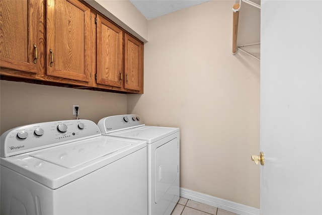 65 Hickory Oak Dr, The Woodlands, TX 77381 - clothes washing area featuring cabinet space, washer and dryer, light tile patterned floors, and baseboards