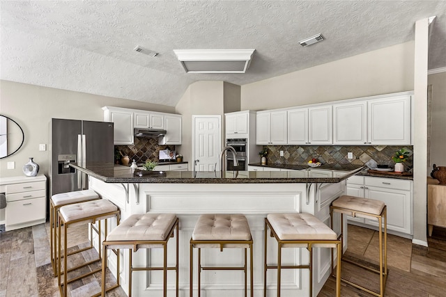 170 April Cv, Montgomery, TX 77356 - kitchen with appliances with stainless steel finishes, white cabinets, backsplash, lofted ceiling, and a textured ceiling