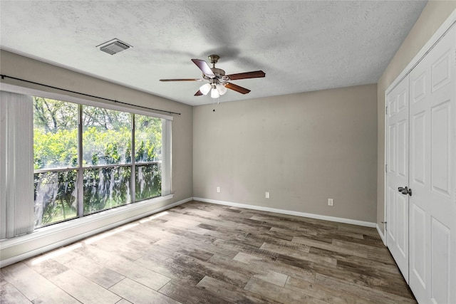 170 April Cv, Montgomery, TX 77356 - unfurnished bedroom with a closet, baseboards, wood finished floors, a textured ceiling, and a ceiling fan