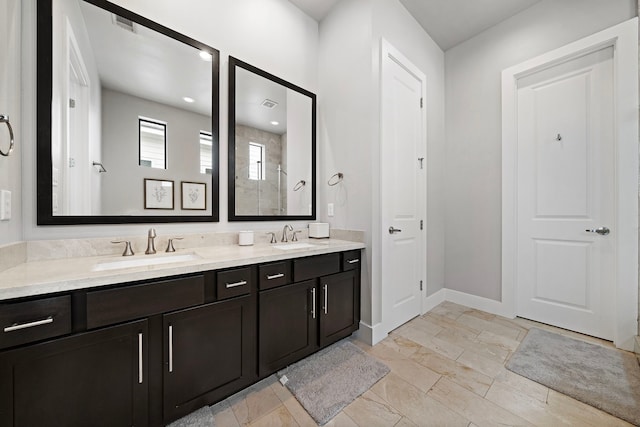 bathroom with a shower stall, double vanity, and baseboards