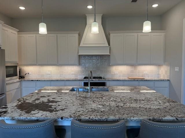 18714 Sweetwater Springs Dr, Cypress, TX 77433 - kitchen featuring premium range hood, a kitchen island with sink, white cabinetry, stainless steel appliances, and decorative backsplash