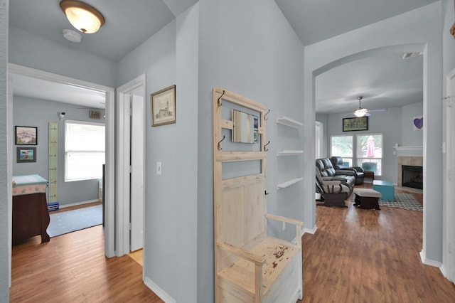 hall with arched walkways, wood finished floors, and baseboards