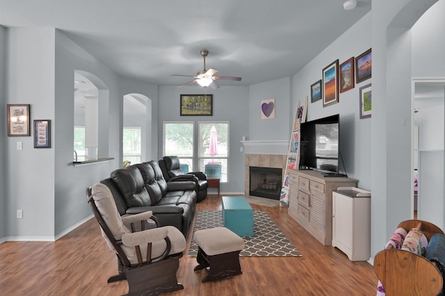 living room featuring healthy amount of natural light, wood finished floors, ceiling fan, and a tiled fireplace