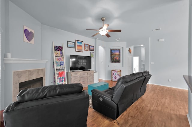 living area with wood finished floors, a ceiling fan, baseboards, and a fireplace