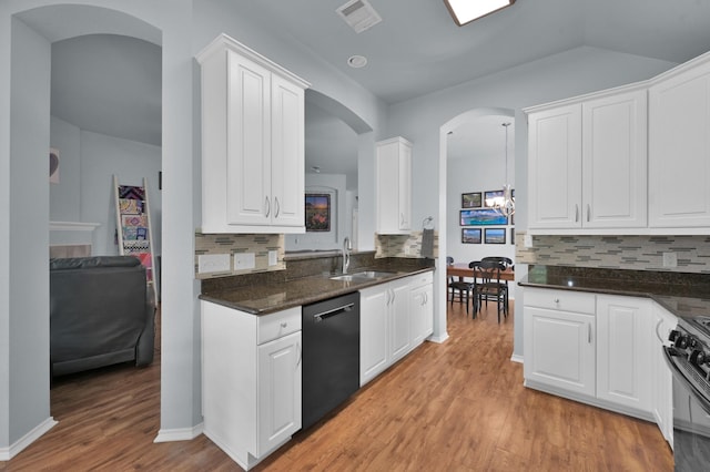 kitchen with dishwasher, a sink, black range with gas stovetop, arched walkways, and backsplash