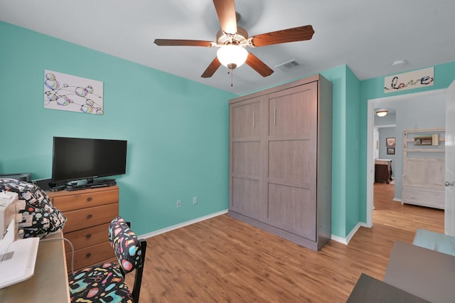 bedroom featuring light wood finished floors, baseboards, ceiling fan, and a closet
