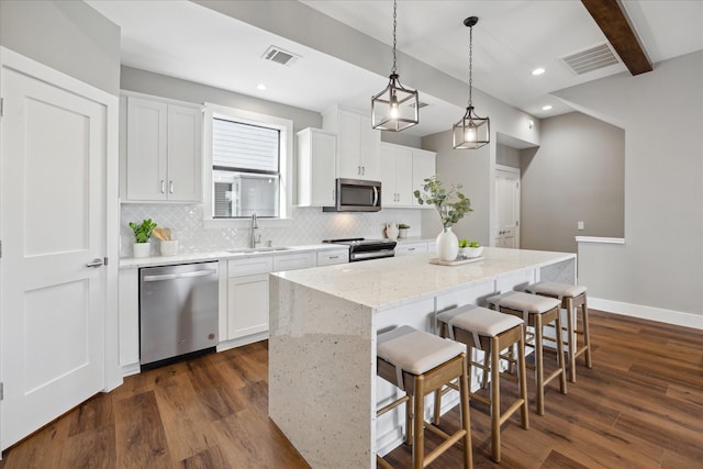 3104 Eunice St, Houston, TX 77009 - kitchen with appliances with stainless steel finishes, decorative backsplash, a kitchen island, dark wood finished floors, and a kitchen breakfast bar