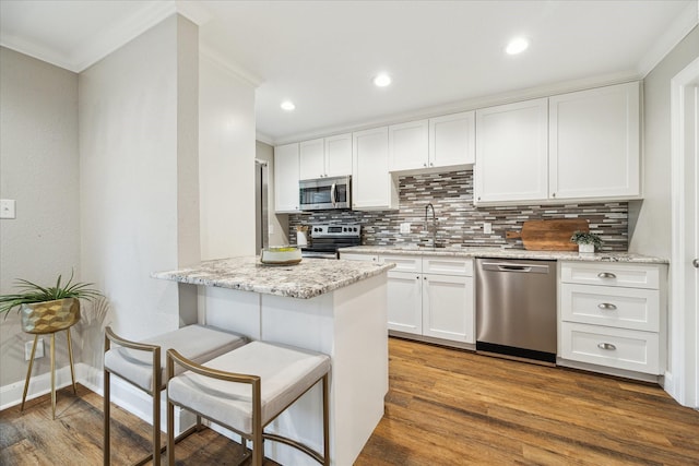 12709 Huntingwick Dr Unit 167, Houston, TX 77024 - kitchen featuring appliances with stainless steel finishes, a sink, crown molding, backsplash, and white cabinets