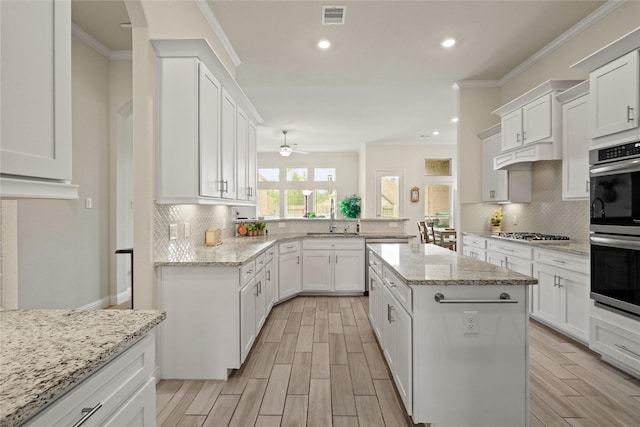 23440 Yaupon Hills Dr, New Caney, TX 77357 - kitchen featuring appliances with stainless steel finishes, decorative backsplash, crown molding, ceiling fan, and white cabinetry