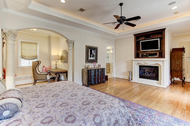 256 S Post Oak Ln, Houston, TX 77056 - bedroom with arched walkways, wood finished floors, a tray ceiling, crown molding, and a glass covered fireplace