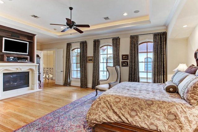256 S Post Oak Ln, Houston, TX 77056 - bedroom with a tray ceiling, wood finished floors, ornamental molding, a glass covered fireplace, and baseboards