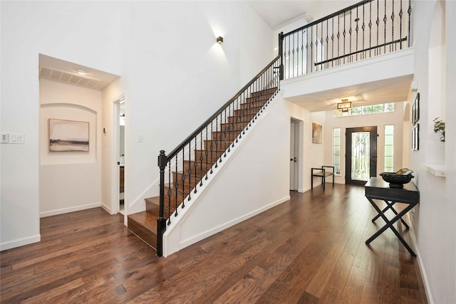 foyer entrance featuring stairway, hardwood / wood-style flooring, a high ceiling, and baseboards