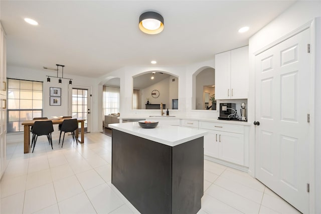 kitchen with a sink, light countertops, a kitchen island, white cabinets, and recessed lighting