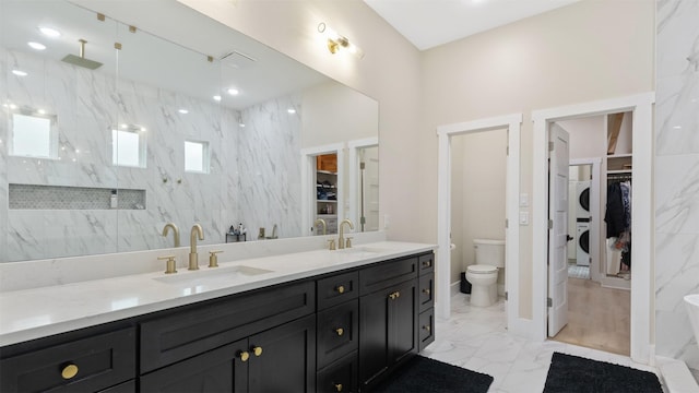 7321 Ponderosa Dr, Magnolia, TX 77354 - bathroom featuring stacked washing machine and dryer, marble finish flooring, a walk in closet, double vanity, and toilet