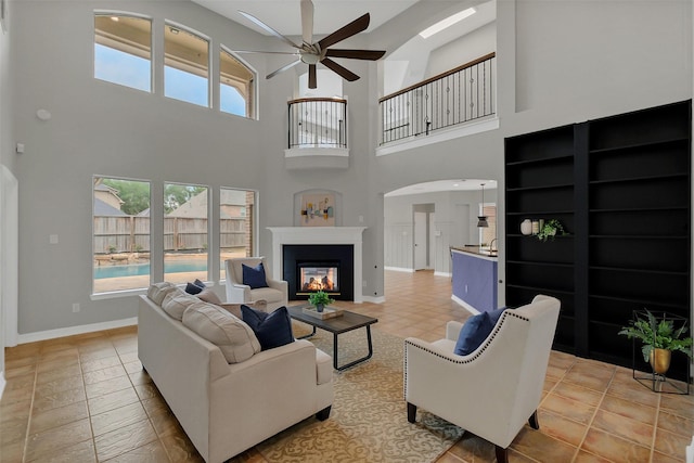 9619 Silver Birch Ct, Missouri City, TX 77459 - living area with ceiling fan, a glass covered fireplace, arched walkways, a towering ceiling, and baseboards