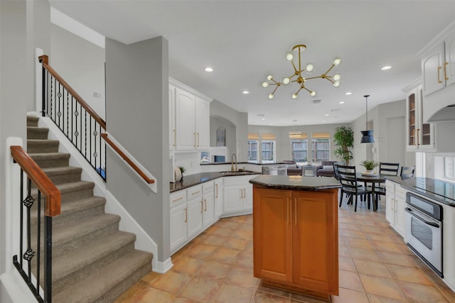 9619 Silver Birch Ct, Missouri City, TX 77459 - kitchen with stainless steel appliances, a sink, a kitchen island, a chandelier, and white cabinets