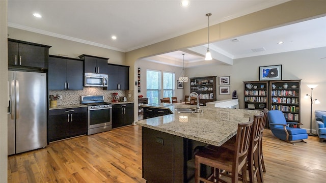 1609 W 24th St Unit B, Houston, TX 77008 - kitchen featuring stainless steel appliances, light wood-style floors, a sink, a kitchen bar, and beamed ceiling