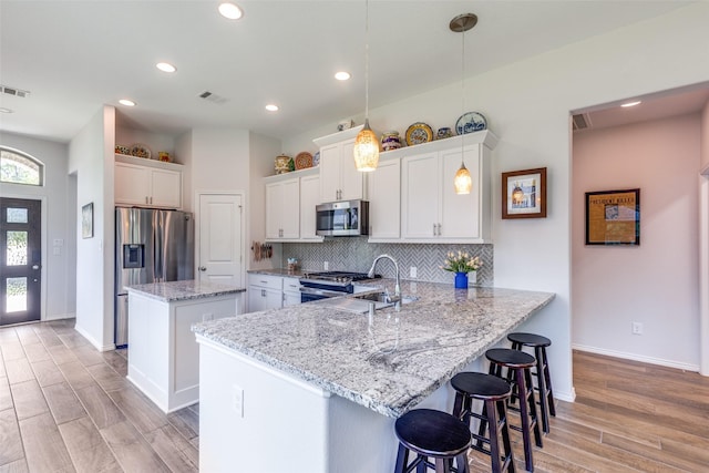 342 Topper Pines Dr, Montgomery, TX 77316 - kitchen with appliances with stainless steel finishes, a kitchen island, a peninsula, light wood-type flooring, and backsplash