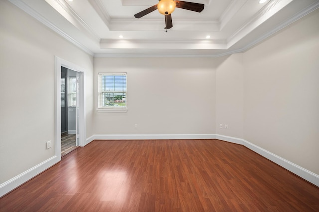 spare room featuring wood finished floors, a tray ceiling, ornamental molding, a ceiling fan, and baseboards