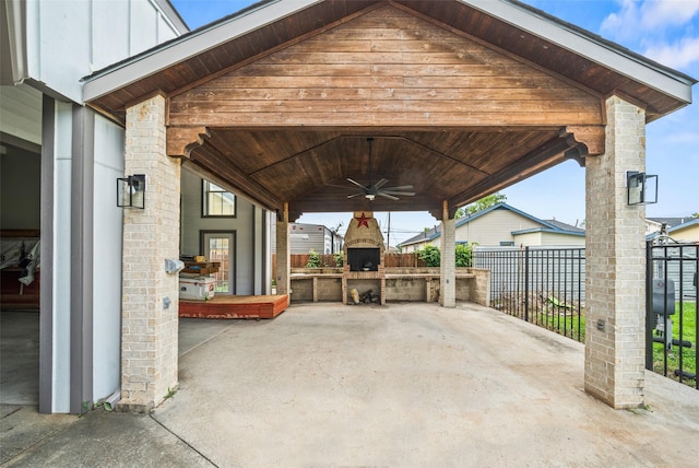 view of patio with a ceiling fan, fence, a gazebo, an outdoor fireplace, and exterior kitchen