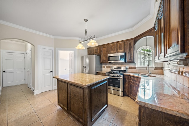 kitchen with stainless steel appliances, arched walkways, a sink, crown molding, and a center island