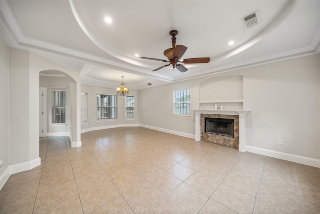 unfurnished living room featuring a raised ceiling, a high end fireplace, a chandelier, light tile patterned flooring, and a ceiling fan