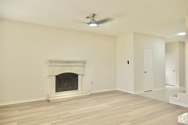 23902 Spring Way Dr, Spring, TX 77373 - unfurnished living room featuring light wood-type flooring, a ceiling fan, a fireplace with raised hearth, and baseboards