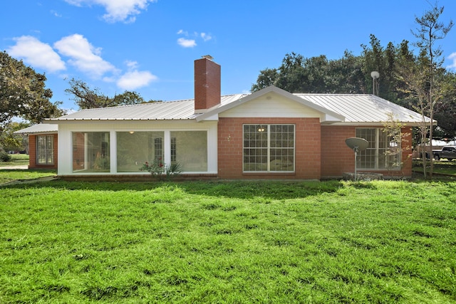 115 Old Caney Rd, Wharton, TX 77488 - rear view of house with a sunroom, a chimney, a yard, and metal roof