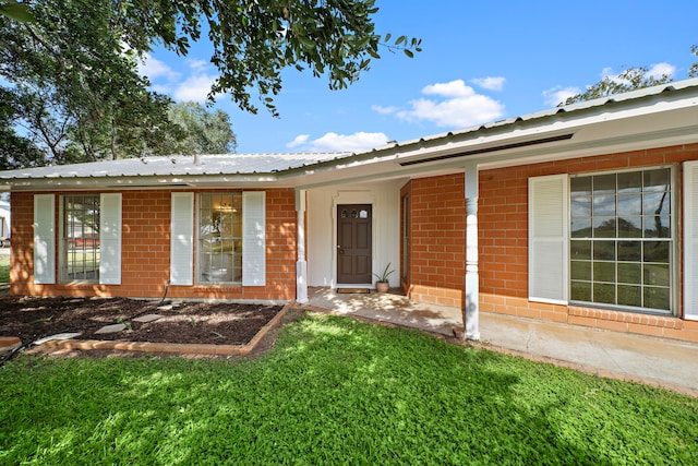 115 Old Caney Rd, Wharton, TX 77488 - view of front of house with metal roof, brick siding, and a front yard